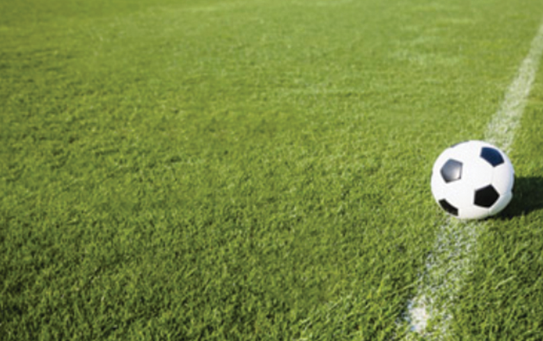Balón de fútbol sobre grama sintética, detalle de cancha